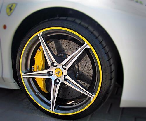 Yellow rim protector wheel guards on the edge of a white Ferrari wheel for ATAM Auto.